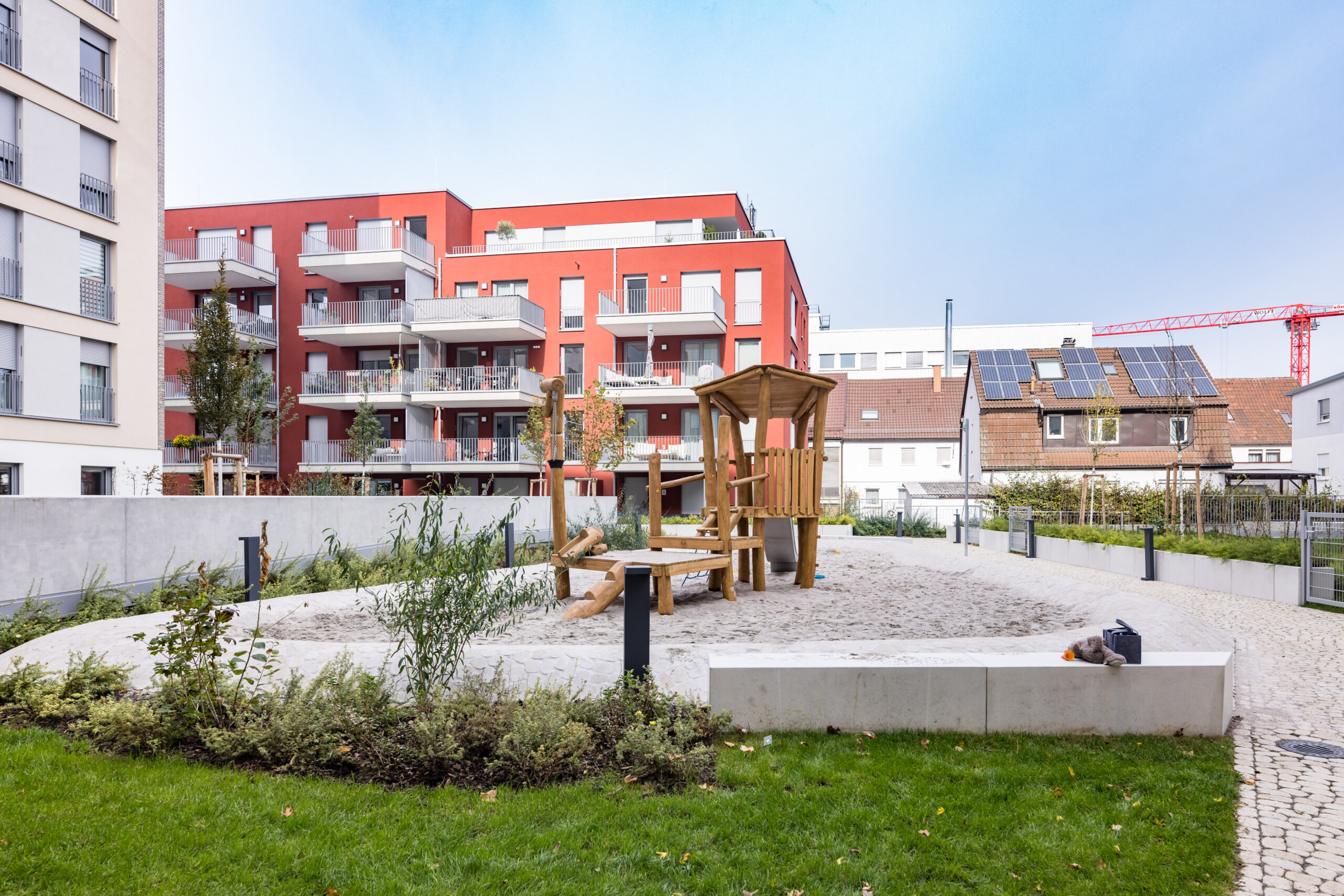 Innenhof Seecarree mit farbigen Mehrfamilienhäusern und einem Holzspielplatz mit Wiese im Vordergrund