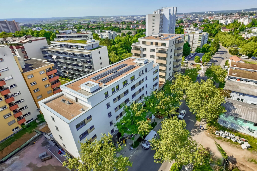 Luftbild eines modernen Wohnkomplexes umgeben von Bäumen, im Hintergrund die Skyline der Stadt Böblingen