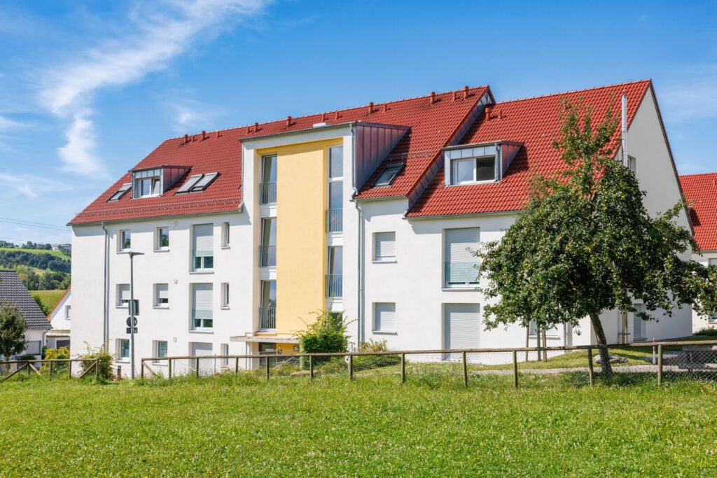 Gepflegtes Mehrfamilienhaus mit großem Rasenstück und umzäunten Vorgarten