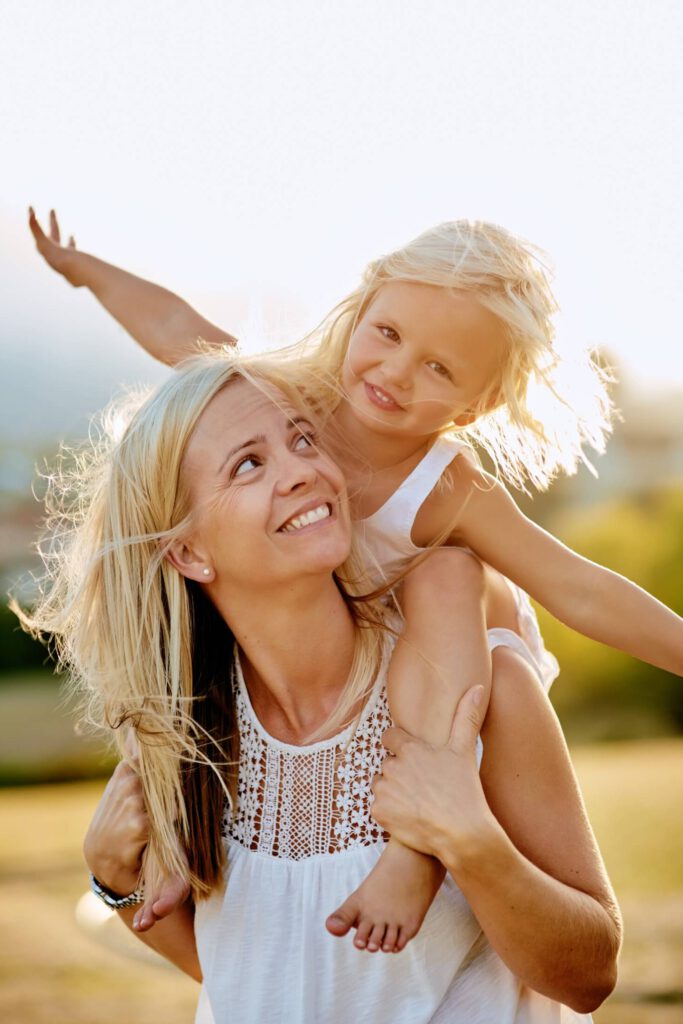 Blonde Frau trägt ihre Tochter auf dem Rücken